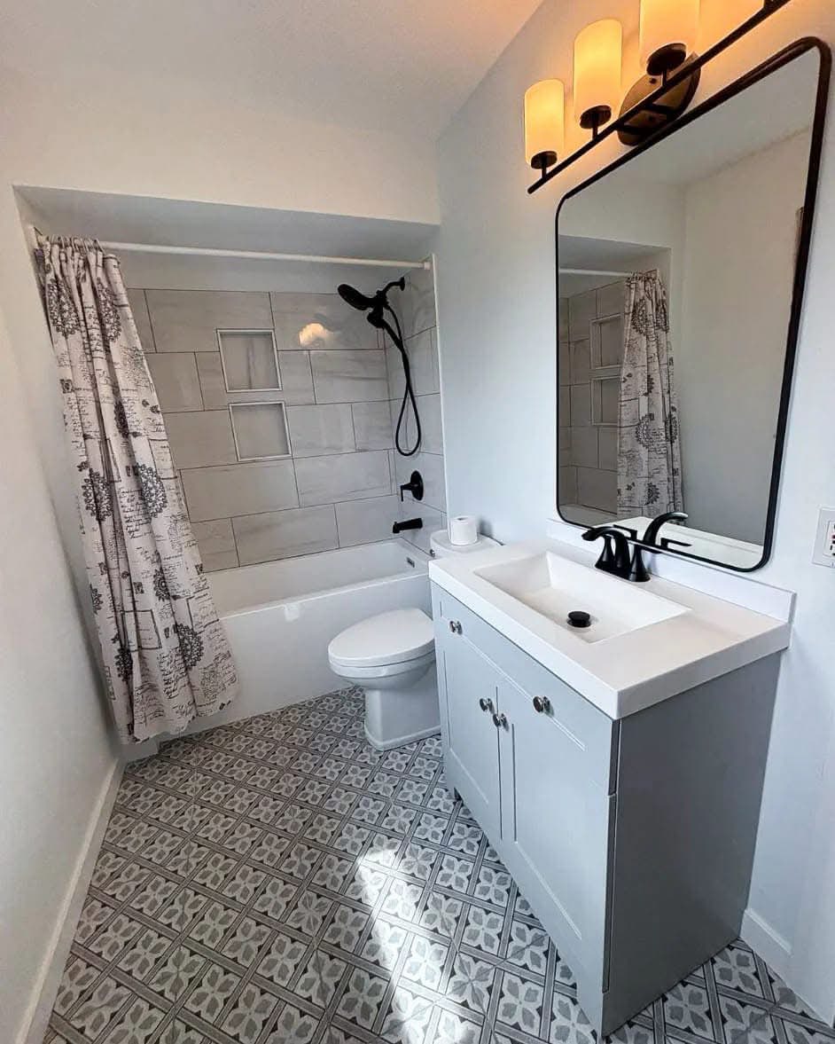 Completed bright bathroom renovation with patterned tile and black fixtures
