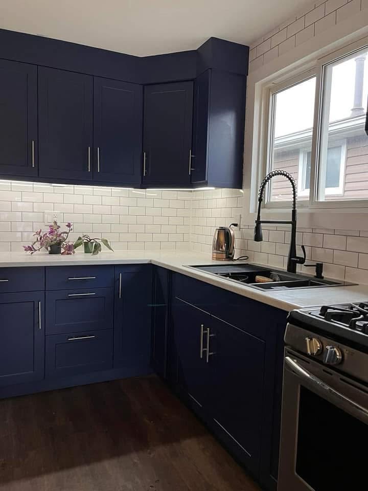 Completed kitchen renovation with navy cabinetry and white subway tile